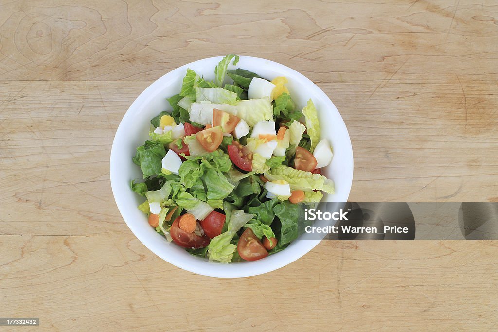 Making Dinner Salad "Salad ingredients in white bowl on old wooden cutting board.  Includes boiled eggs, tomatoes, carrots, lettuce, onions, raisins." Boiled Egg Stock Photo