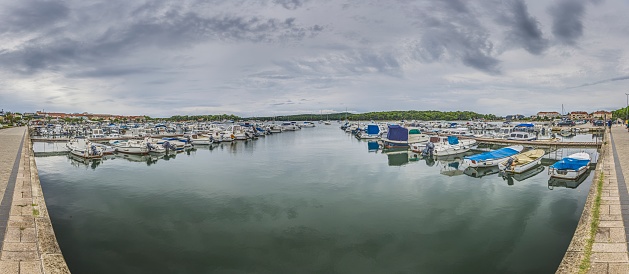 View over a yacht harbor with docked ships in front of clouded sky in summer