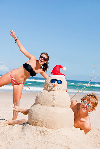 Christmas people having fun at beach with snowman stock photo