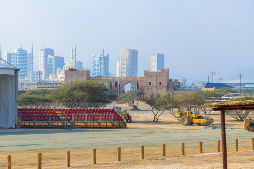 The skyline of modern Fujairah with a mosque among the modern architecture and a historic Arabic building in the forefront in Fujairah, United Arab Emirates