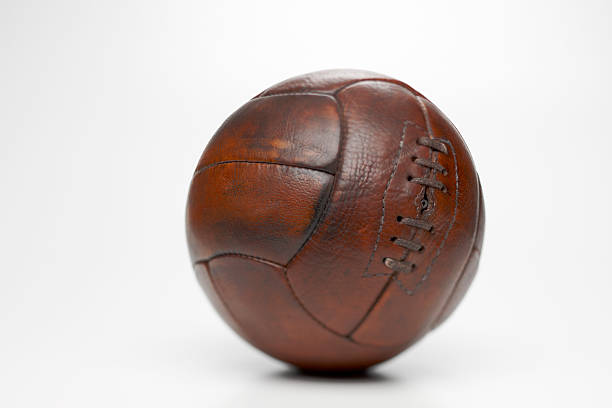 Water and mud fly as an AFL ball is kicked in front of a black background