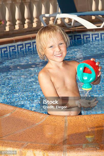 Boy With Watering Can In The Swimming Pool Stock Photo - Download Image Now - Blond Hair, Blue, Boys