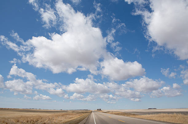 istock Highway on prairie with puffy white clouds in blue sky 177335977