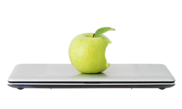 green apple in a closed laptop green apple in a closed laptop apple with bite out of it stock pictures, royalty-free photos & images