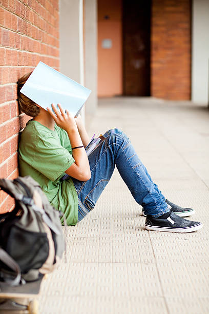 istock frustrated high school boy using book cover his face 177336893