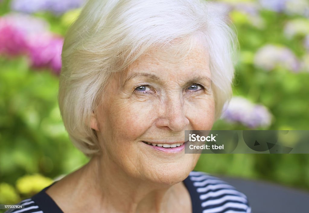 Senior woman  outdoors "Senior woman portrait, outdoors, in front of the garden, smiling to camera" 70-79 Years Stock Photo