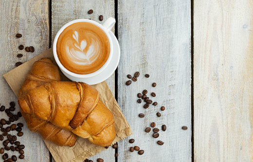 Chocolate croissants. Delicious breakfast on the table. Tasty sweet baking dessert for coffee. Food background. Fresh buttery croissants rolls. Coffee grains.A cup of coffee. Flat lay. Top view.