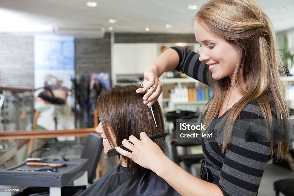 Hairdresser Cutting Client's Hair Hairdresser cutting client's hair in beauty salon. Hair Salon Stock Photo