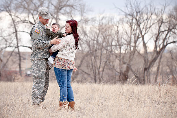 Military family hugging in field stock photo