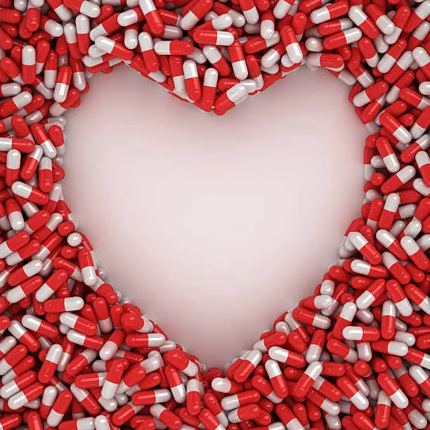 Symbol of heart made from red capsules on the white background