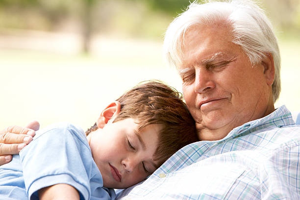 Grandfather And Grandson Taking Nap Together Grandfather And Grandson Taking A Nap Together In The Park sleeping grandpa stock pictures, royalty-free photos & images