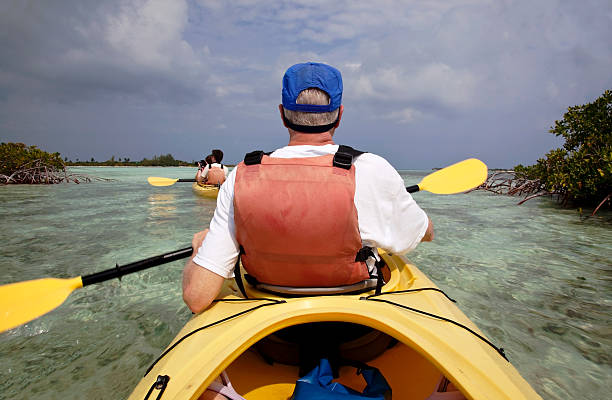 Family kayaking "Older middle-aged man and two older children (boy and girl) kayaking through the mangroves off Providenciales, Turks and Caicos Islands." providenciales stock pictures, royalty-free photos & images