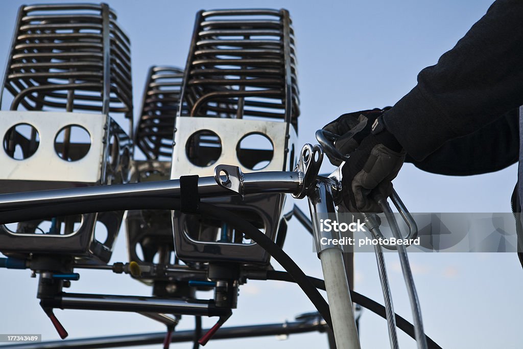 Hot Air Balloon Assembly Teamwork Assembly of a hot air balloon preparing for a flight.  Attaching the gondola to the burner frame that will be below the balloon canopy.  Showing preparation and work. Black Color Stock Photo