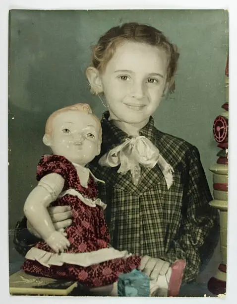 Hand-tinted with color in fine details vintage photo of girl with doll -circa 1950