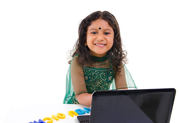 E-learning "Little Indian girl using a laptop on table, isolated on white background" beautiful traditional indian girl stock pictures, royalty-free photos & images