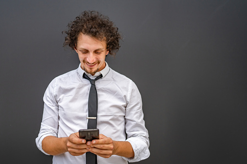 One caucasian man male businessman use smartphone mobile phone to make a call or send sms text messages texting online stand outdoor wear white shirt happy confident success real person copy space