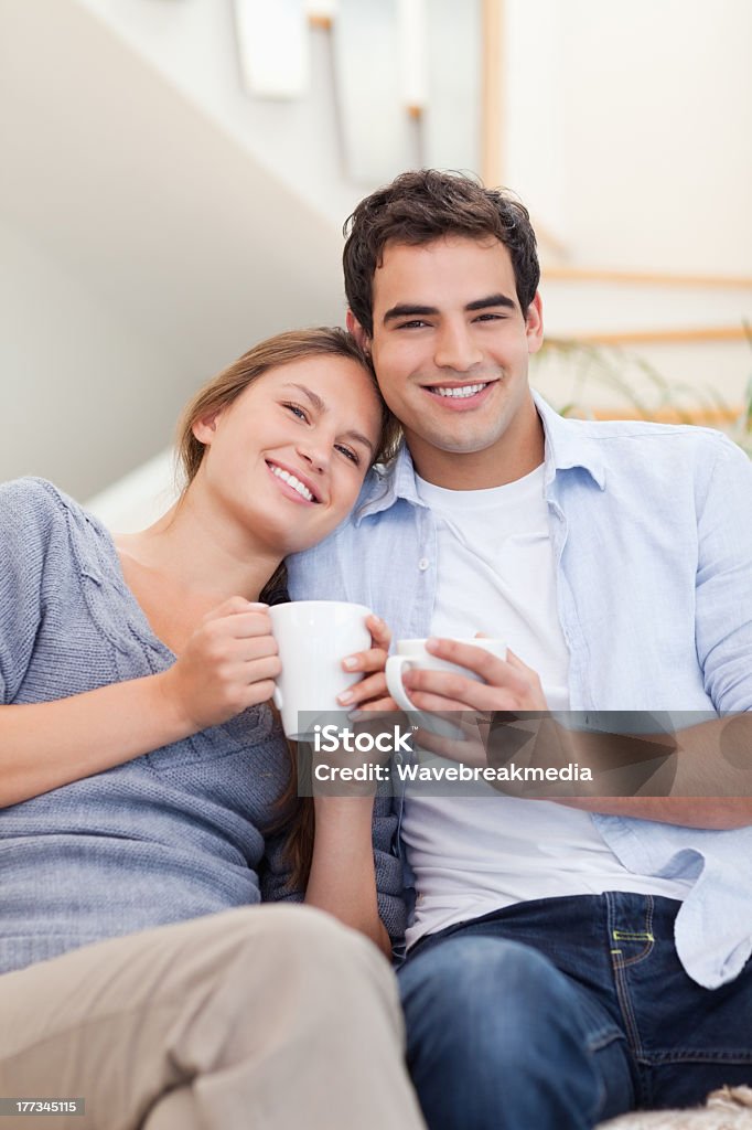 Portrait of a couple drinking coffee Portrait of a couple drinking coffee in their living room 20-24 Years Stock Photo