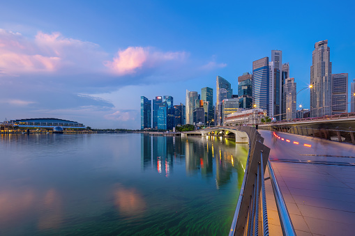 Warm light of sunrise illuminating the skyscrapers, hotels and apartment buildings of Singapore’s Central Business District overlooking the tranquil waters of Marina Bay.