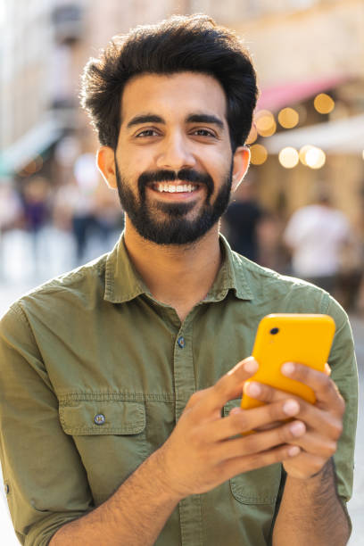 istock Young man use smartphone typing text messages browsing internet finishing work looking at camera 1773472336