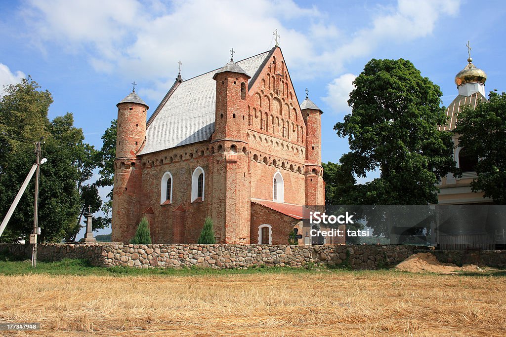 16th century fortified church in Belarus village "Horizontal color photo of the early 16th century fortified church in Belarus village (Synkaviiy, Hrodna region). The defensive system of the church consists of four towers and arrow-loops placed under the vaults. The walls are about 1.5m thick. The building has elements of Roman and Gothic architecture.  It is one of the two such churches in Belarus and it is quite unique that it was almost unchanged during the centuries. This site was added to the UNESCO World Heritage Tentative List in 2004 in the Cultural category." 16th Century Stock Photo