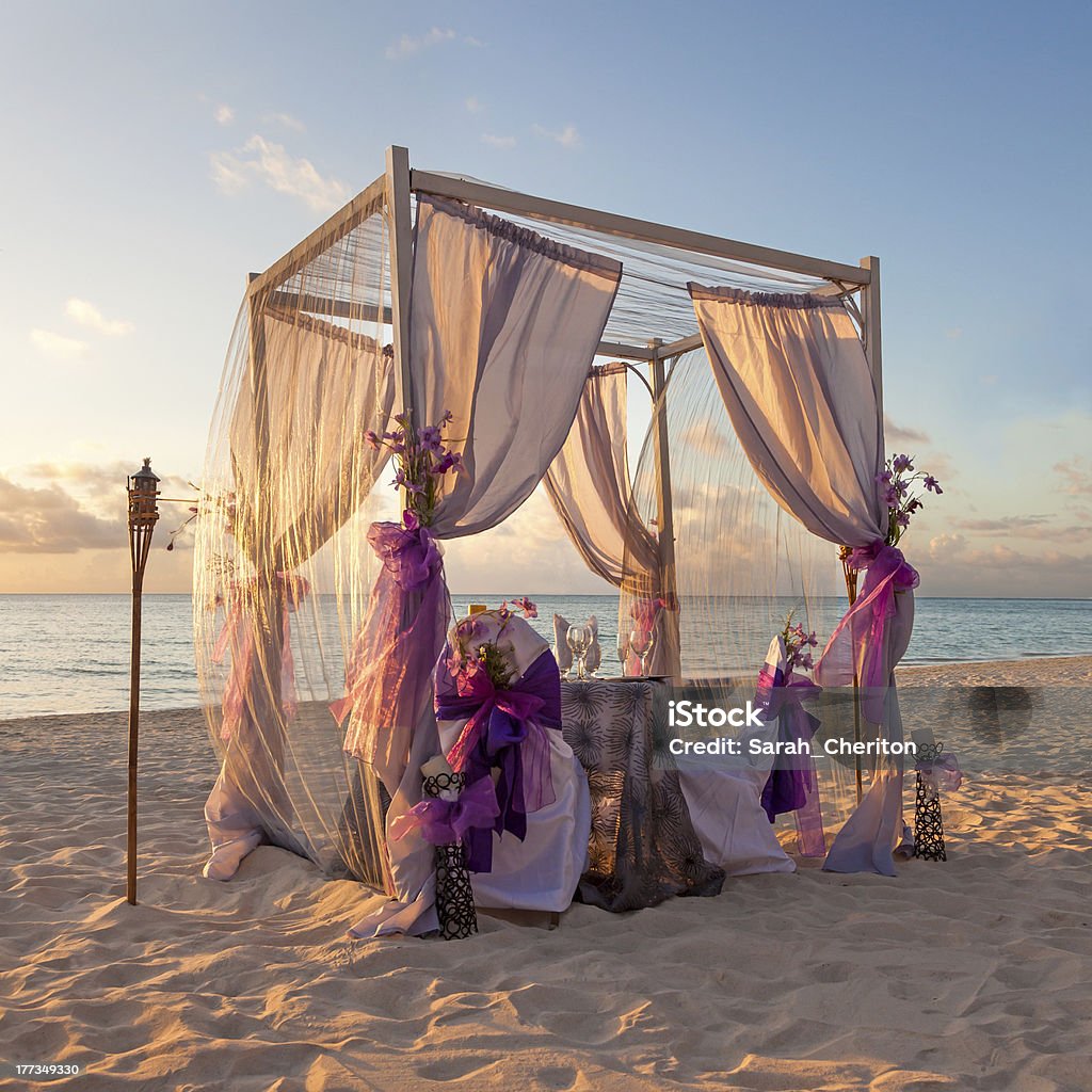 Decorative canopy on Caribbean beach at sunset Beautiful Decorated Romantic Wedding Table on Sandy Tropical Caribbean Beach at Sunset Wedding Stock Photo