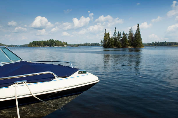 Boat Docked at Cottage Speed Boat docked at the cottage on a crystal clear northern Ontario lake. cottage life stock pictures, royalty-free photos & images
