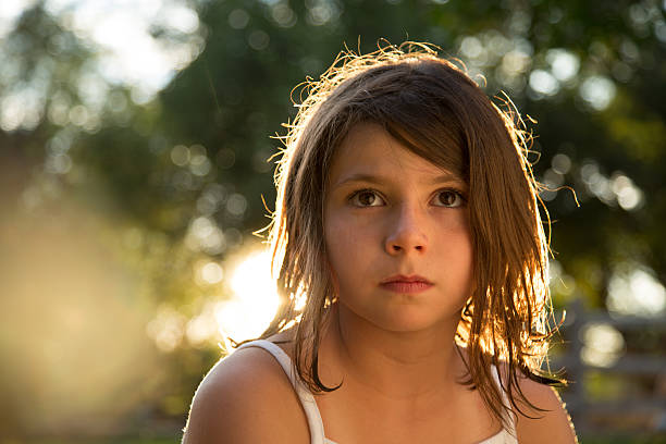 Young girl sitting outside backlit by the sun