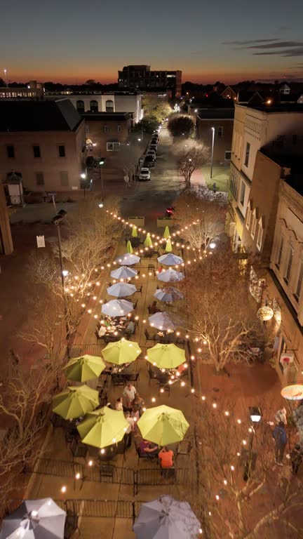 Nightlife of sidewalk cafe on Queens Wy Street in Hampton, Virginia. Aerial vertical footage with backwards-tilt down camera motion