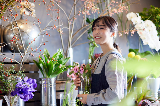 A Japanese woman wearing an apron working at a flower shop