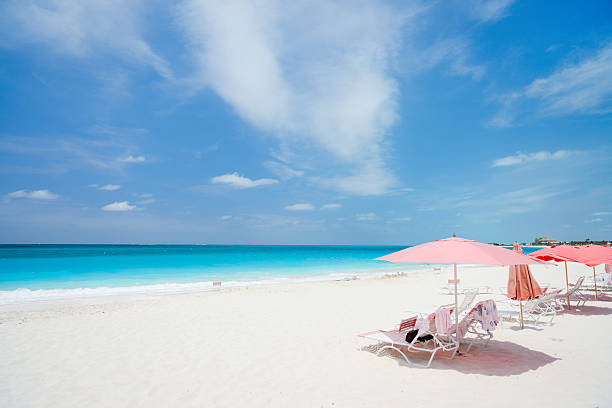 Tropical beach Pink umbrellas on beautiful beach at Providenciales island in Turks and Caicos providenciales stock pictures, royalty-free photos & images