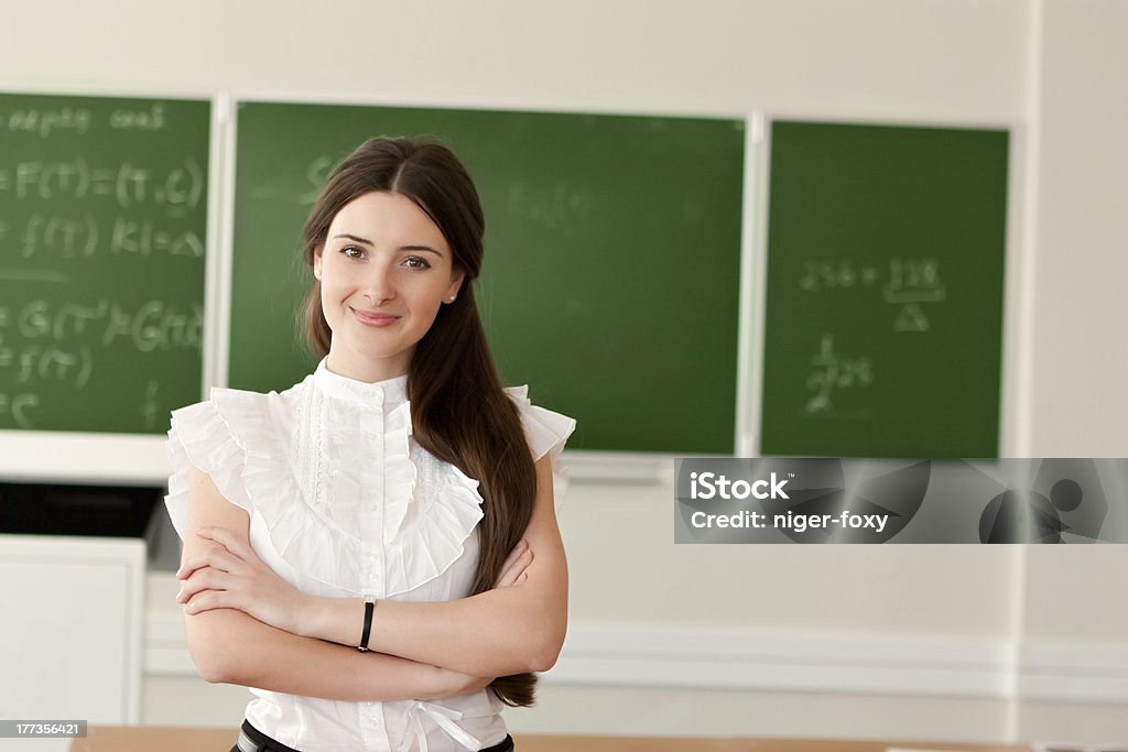 teacher on background of blackboard The teacher in the classroom on blackboard background. Adult Stock Photo