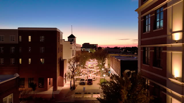 Dramatic sky above the alley in Hampton, Virginia. Sunset covers Queens Wy Street with string light in Downtown District. Aerial footage with forward camera motion