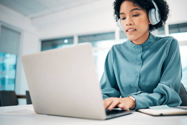 headphones, laptop and woman typing in the office doing research for creative project. computer, technology and professional female designer working, planning and listening to music in workplace. - social housing audio imagens e fotografias de stock