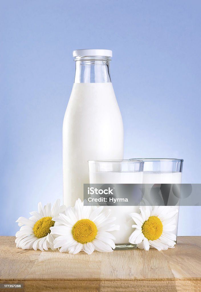 Bouteille, verre de lait et à la fleur de camomille est table en bois - Photo de Bouteille de lait libre de droits