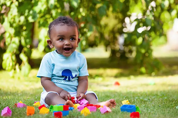 Photo of African american baby boy playing in the grass