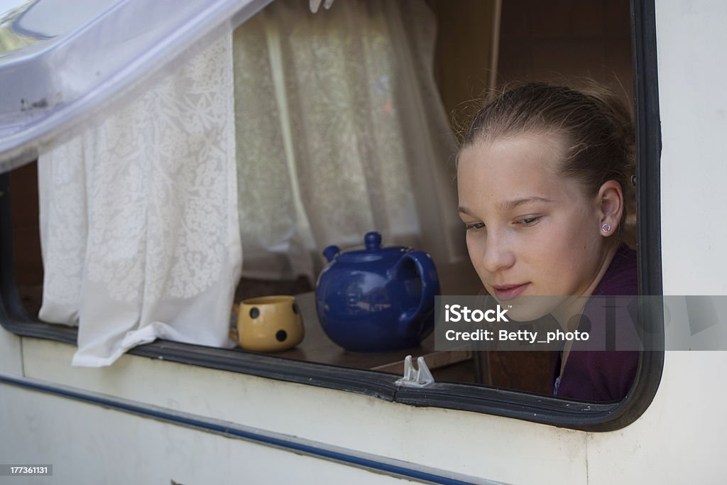 girl sitting in a caravan teenage girl sitting in an old trailer looking out of the window Adolescence Stock Photo