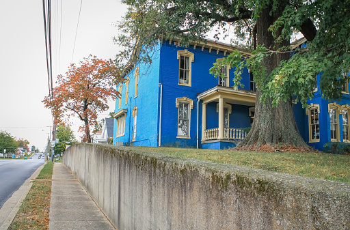 A blue historic house with a concrete retaining wall in Elizabethtown, Kentucky