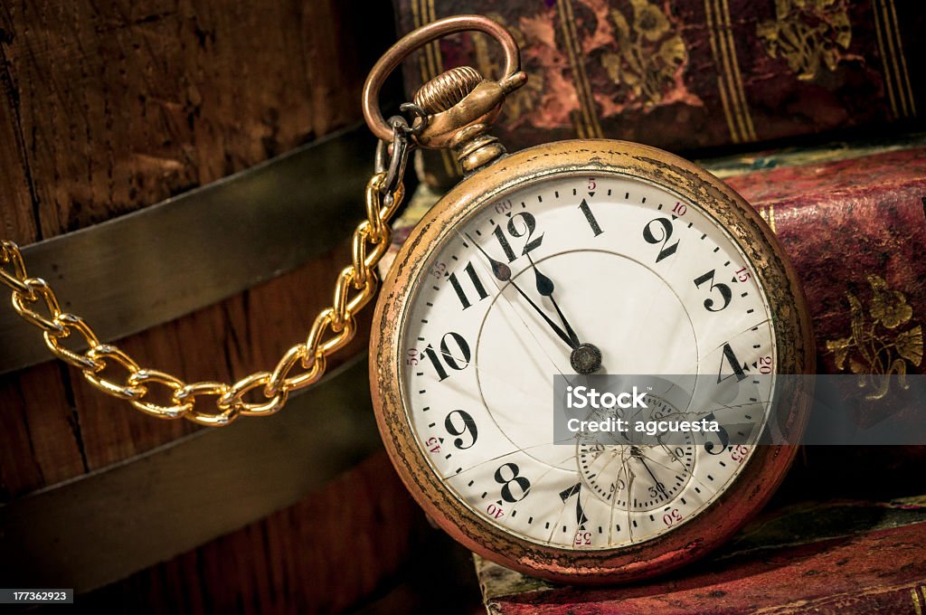 Vintage gold pocket watch on books Antique pocket clock showing a few minutes to midnight over ancient books in Low-key. Concept of time,the past or deadline. Broken Stock Photo