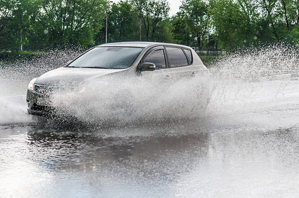 spray from the car Car rides on big water in the rain puddle stock pictures, royalty-free photos & images