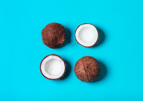Broken and whole coconut in minimal style. Ripe coconuts on a light blue background. Creative summer concept, pop art design. Organic food