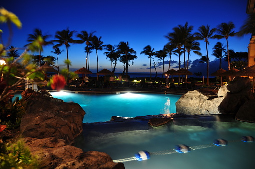 View of ocean from luxury hotel at night, Kaanapali, Maui, Hawaii with palm trees.