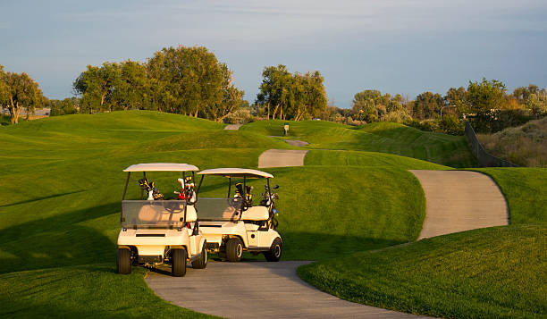 paar golfwagen auf den grünen golfplatz bei sonnenuntergang - country club fotos stock-fotos und bilder