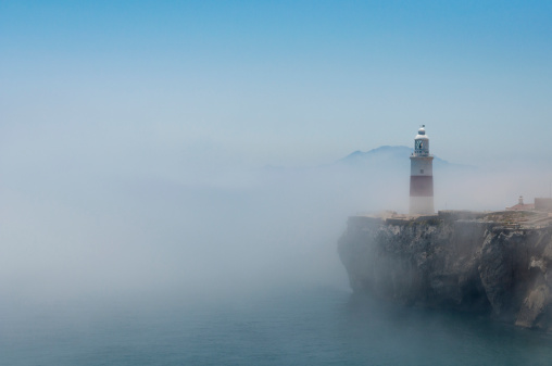 Gibraltars lighthouse at Europa Point standing in the mist with Africa in the distance.