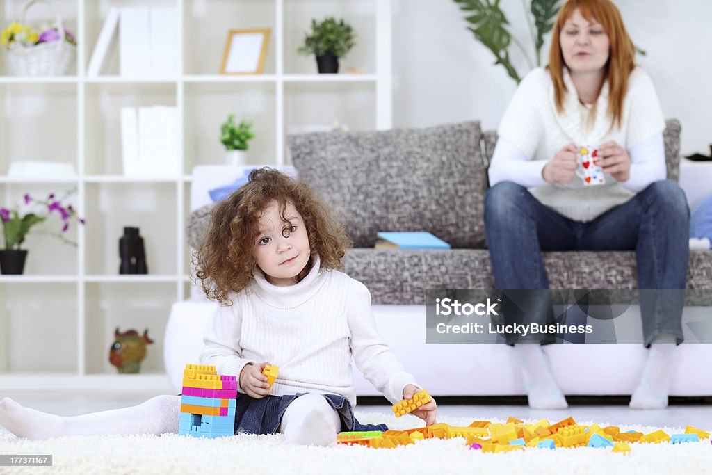 mother kept the child "child playing on carpet in living room, in background mom looking in child" Adult Stock Photo