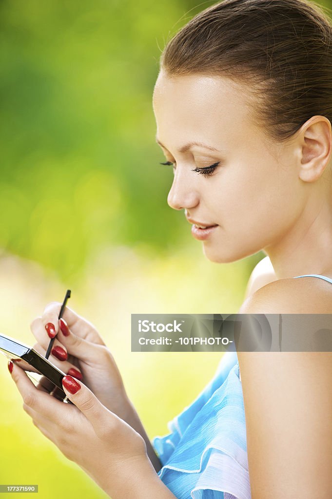 Portrait of young woman working with smartphone Portrait of young pretty woman working with smartphone and stylus at summer green park Adult Stock Photo