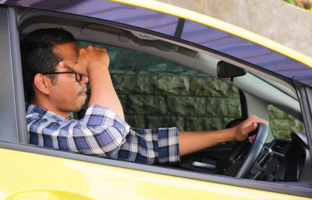 un homme conduisant sa voiture avec une expression de stress - pusing photos et images de collection