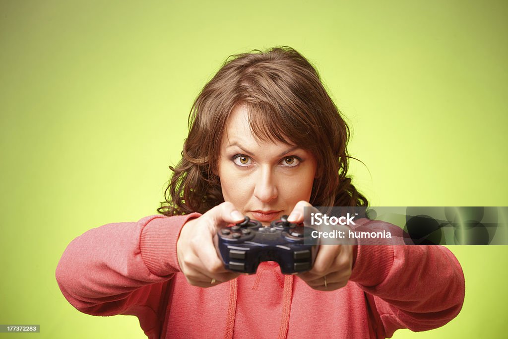 Beautiful womanl with gamepad playing vieogame Beautiful womanl with gamepad playing vieogame over green background. Focus on face Adult Stock Photo