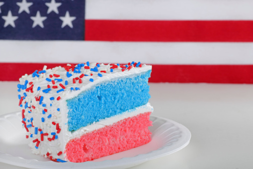 Piece of red white and blue cake with american flag in background