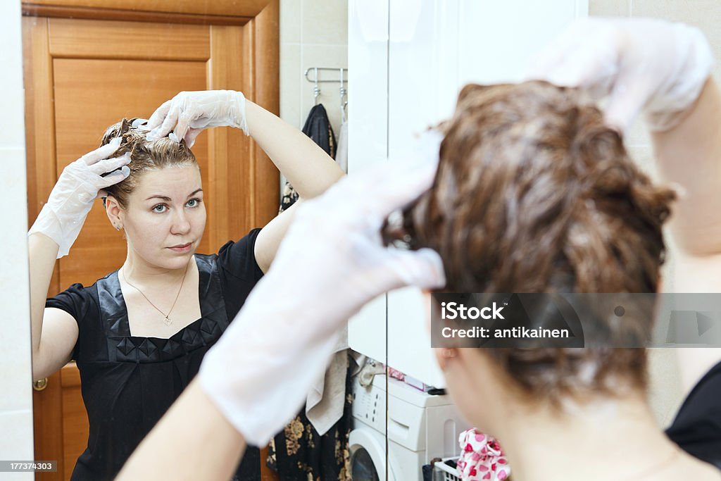 Woman dyeing hairs at home Portrait of pretty Caucasian beautiful female dyeing hairs at domestic bathroom Hair Dye Stock Photo