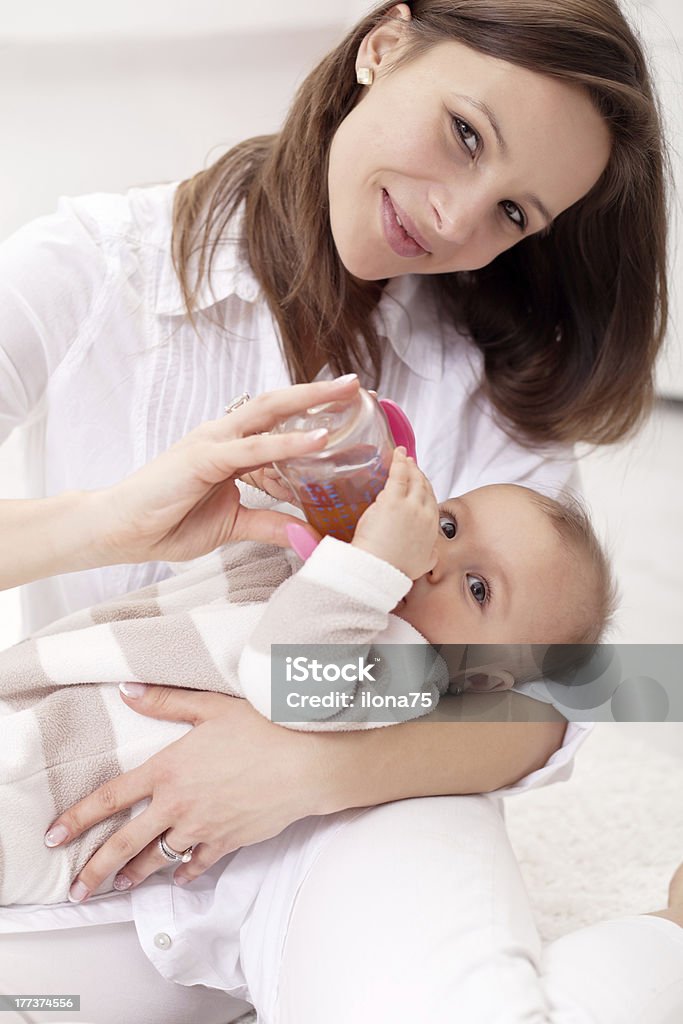 Baby girl held by her mother Baby girl held by her mother - drinking from nursing bottle Tea - Hot Drink Stock Photo